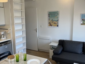 A modern kitchen with white cabinetry, a coffee machine, and a dining table set with plates and glasses.