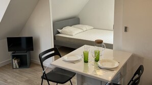 Ein kleiner, moderner Raum mit Bett, Fernseher und einer Essecke mit Tisch und zwei Stühlen.