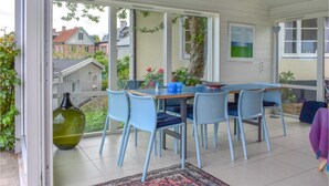 Uma área de refeições com mesa, cadeiras, uma janela grande e vista para casas.