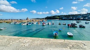 A harbor with numerous boats docked, a stone wall, and buildings in the background. - Charming 3-bed House, Saint Ives, nr Beach & Town (St Ives)