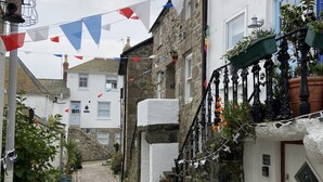 A narrow cobblestone street flanked by stone buildings with balconies, potted plants, and a sign reading "Armenia Nodin". - Charming 3-bed House, Saint Ives, nr Beach & Town (St Ives)