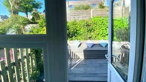 A wooden deck with a view of a house and surrounding greenery. - Charming 3-bed House, Saint Ives, nr Beach & Town (St Ives)