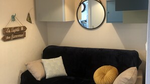 A dark blue sofa with multiple cushions, a hanging light fixture, and a wall-mounted mirror.