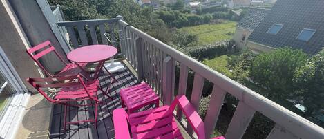 Un balcón con una mesa y sillas, con vistas a una zona residencial con casas y vegetación.