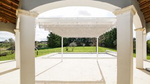 Een open paviljoen met uitzicht op een gazon en bomen.