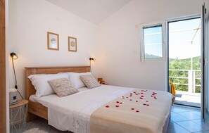 A bedroom with a wooden bed, two bedside lamps, a window with a view, and a small table with a lamp. - 2 bedroom nice home in Molat (Molat)