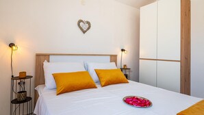 Een slaapkamer met een bed, twee nachtkastjes, een wandlamp en een kledingkast.
