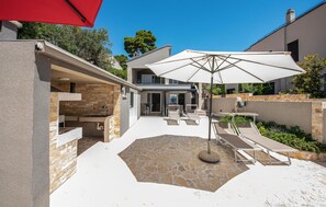 A modern outdoor patio with stone flooring, a built-in barbecue, and outdoor seating. - Beautiful apartment in Petrcane with WiFi (Petrcane)