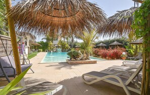 A pool area with lounge chairs, a water fountain, and thatched umbrellas. - Cozy home in Pozzallo with outdoor swimming pool (Pozzallo)