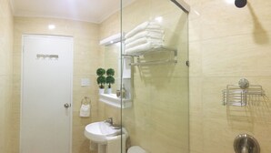 A bathroom with a white door, a sink, a glass shower enclosure, and shelves with towels and toiletries. - Palm Beach Stunning Villa 13-beds 10-baths -26ppl (Noord)