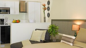 A compact hotel room with a kitchenette, a bed with pillows, a bedside table with a plant, and a lamp. - Palm Beach Stunning Villa 13-beds 10-baths -26ppl (Noord)