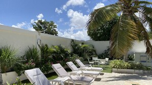 A poolside area with white lounge chairs, a small table, and a pool. - Palm Beach Stunning Villa 13-beds 10-baths -26ppl (Noord)