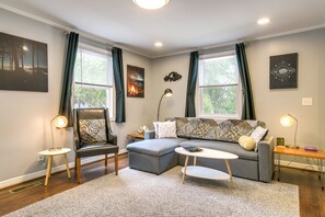 Relax in this stylish living room with a comfortable sofa, coffee table, and side table, surrounded by unique lamps and artwork.