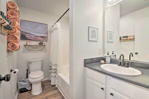 A bathroom with a white toilet, a sink with a mirror, and towels on a rack.