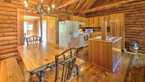 A rustic wooden cabin interior with a dining table, chairs, a refrigerator, a microwave, and a sink. - Rustic Zanesville Getaway w/ Expansive Yard! (Zanesville)