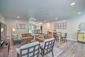 A modern living room with a sofa set, a dining table, and chairs. There is a kitchen area in the background. - Lakefront Townville Gem w/ Boat Dock & Kayaks (Townville)