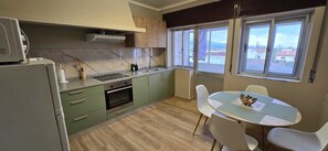 Una cocina compacta con horno integrado, microondas y ventana con vista a una zona residencial.