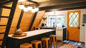 Eine Küche mit Holzbalkendecke, einer Kochinsel mit Sitzgelegenheiten und einem Fenster.