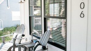 Een veranda met Adirondack-stoelen, een houten terras en huisnummer 106.