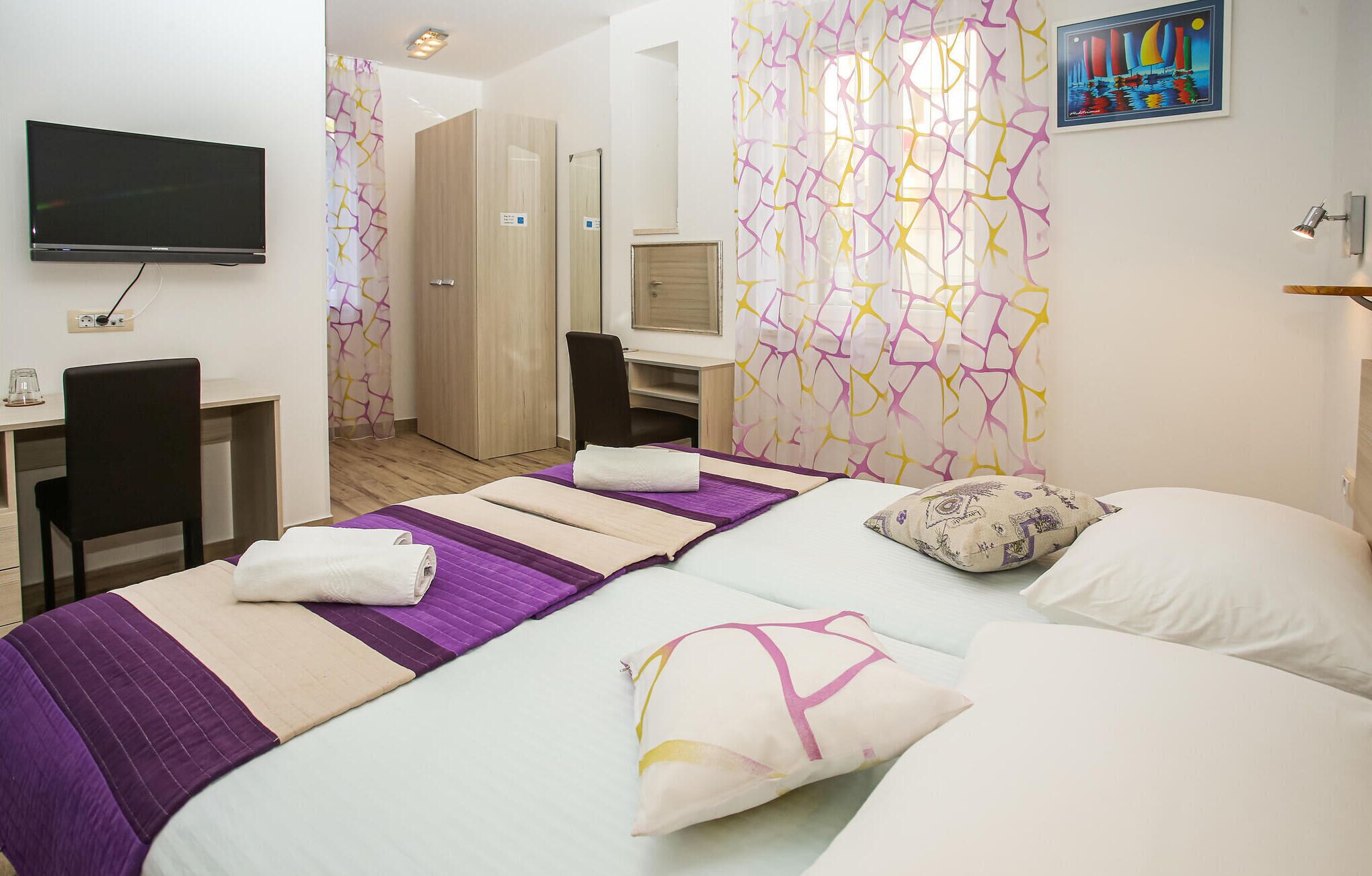 Habitació d'hotel amb llit, escriptori, cadira, televisió i zona de dutxa.
