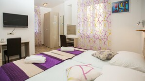 Une chambre d’hôtel équipée d’un lit, d’un bureau, d’une chaise, d’une télévision et d’un espace douche.