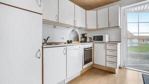 Een moderne keuken met witte kastjes, een roestvrijstalen spoelbak, een magnetron en een fornuis.