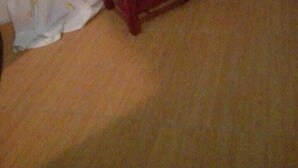 Une pièce avec un téléviseur posé sur un meuble en bois, une prise électrique au mur et un rideau à motifs.
