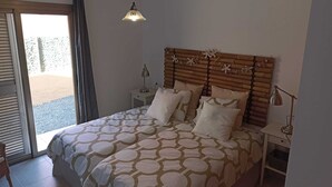 Une chambre à coucher avec un lit, des tables de chevet, une lampe suspendue et une vue par la fenêtre.