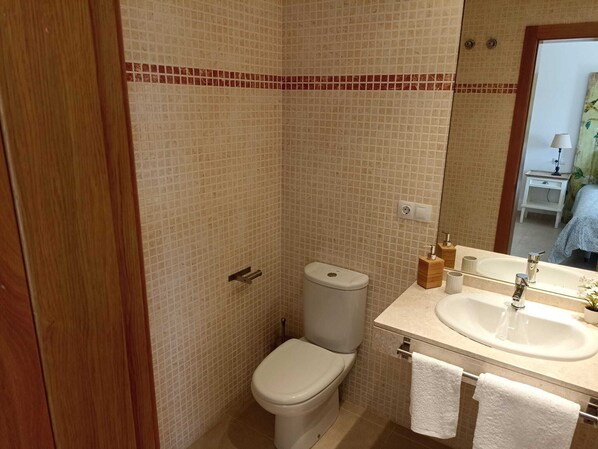 A bathroom with a toilet, sink, and mirror.