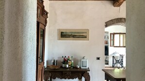 A rustic kitchen with a wooden table, a framed picture on the wall, and a window with a view.