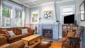 Una sala de estar con chimenea, sofá, mesa de centro y televisor.