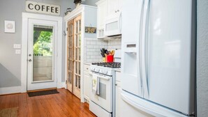 Una cocina con armarios blancos, un refrigerador blanco, una estufa y una puerta que dice 'COFFEE'.