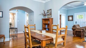 Un comedor con una mesa y sillas de madera, una estantería y una araña.