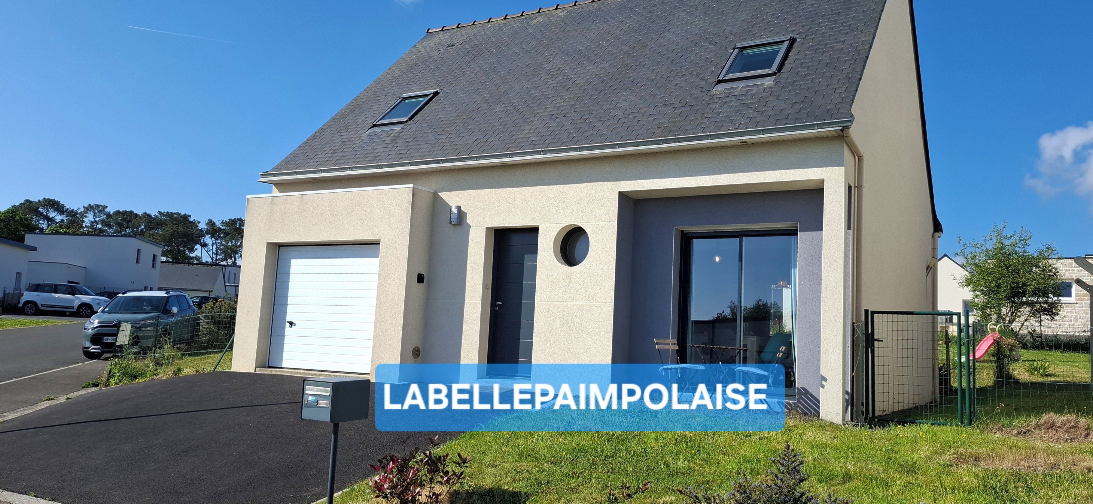 Ein modernes, zweistöckiges Haus mit Garage, Eingangstür und einem kleinen Fenster im Obergeschoss.