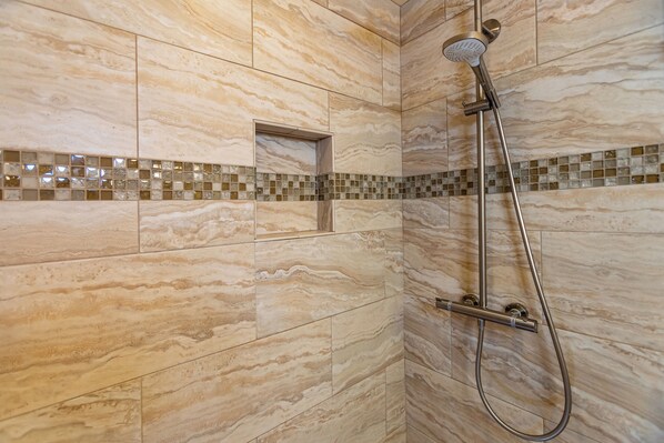 A shower with a handheld showerhead and a handheld shower attachment.