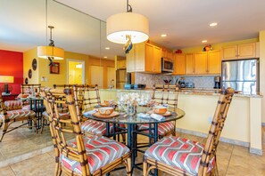 Una cocina moderna con una mesa de comedor redonda, sillas de bambú y una isla central.