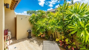 A courtyard with a pergola, a water feature, and lush tropical plants.