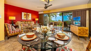 A dining area with a glass table, red walls, and a view of the ocean.