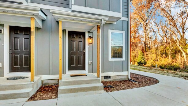 Une maison moderne à deux étages, dotée d’un porche à l’avant, d’une porte de garage et d’une pelouse bien entretenue.