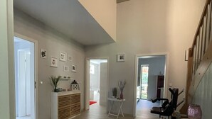 Een ruime woonkamer met een groot tapijt, een trap en een eethoek met een tafel en stoelen.