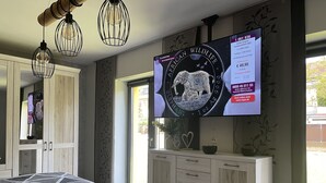 Een slaapkamer met een bed, een houten garderobe en een televisie waarop een reclame voor een horloge wordt getoond.