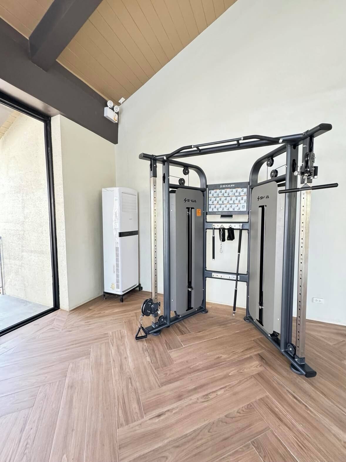 Un gimnasio con barra de dominadas, máquinas de pesas y un televisor instalado en la pared.