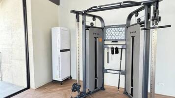 Un gimnasio con barra de dominadas, máquinas de pesas y un televisor instalado en la pared.