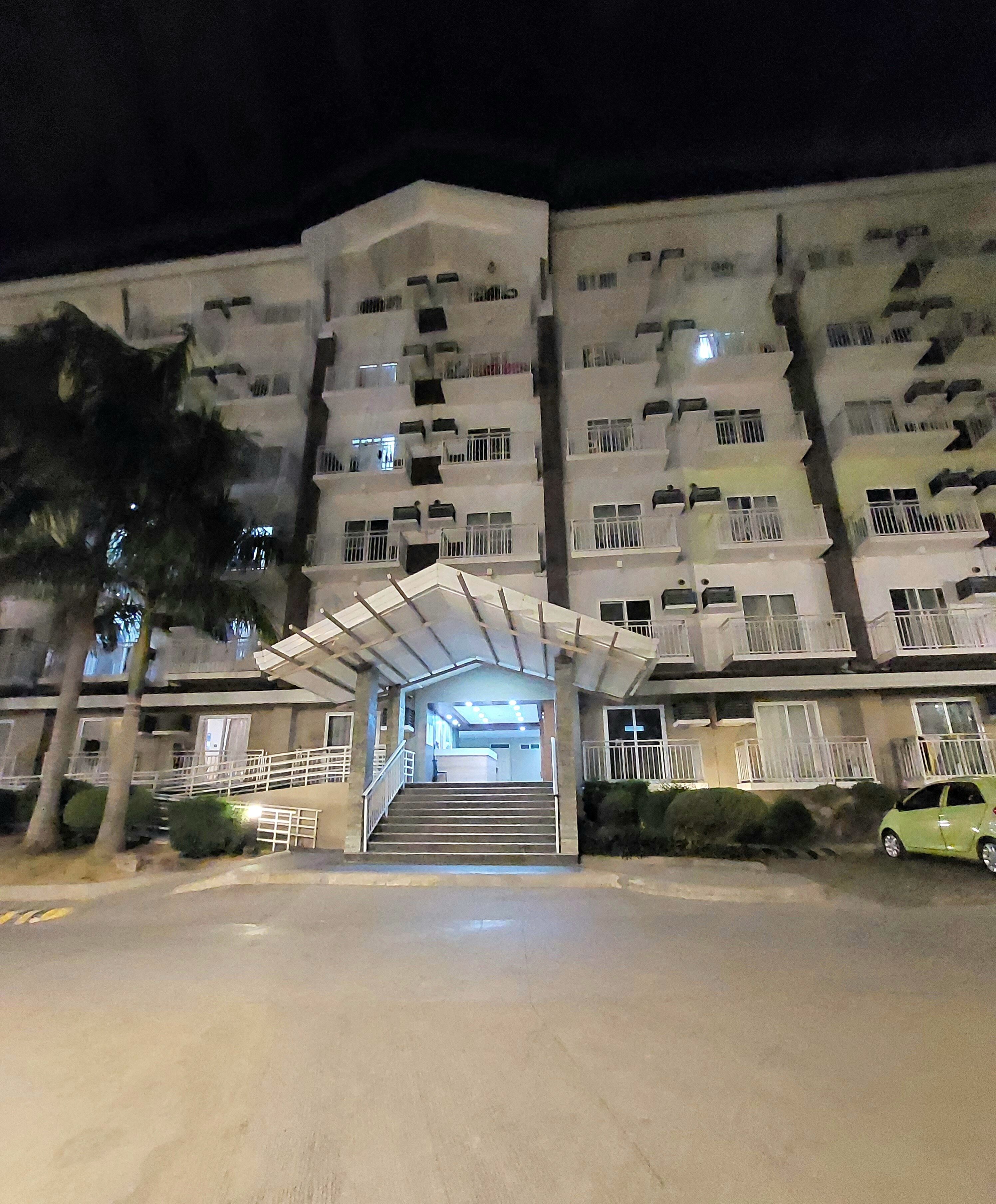 A multi-story building with a central entrance, staircases, and a covered walkway.