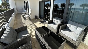 Un balcon doté de meubles en osier, d’une porte vitrée et offrant une vue sur l’océan.