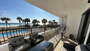 Un balcon agrémenté de meubles en osier, une piscine et une vue sur la plage.