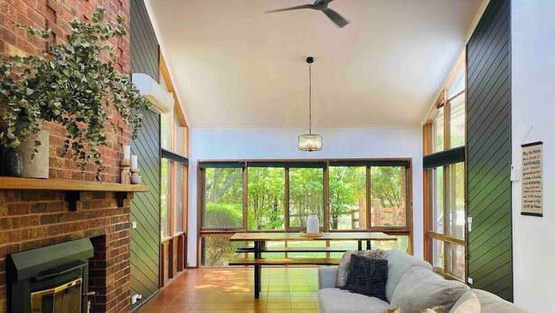 Una sala de estar acogedora con chimenea, un sofá y una mesa de comedor con vistas al exterior.