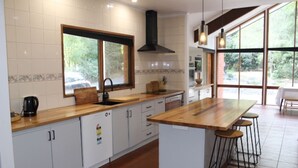 Una cocina moderna con armarios blancos, encimera de madera, un ventanal grande y una isla central con taburetes.