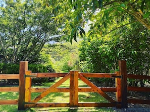 A wooden gate with a crossbar in the center, surrounded by lush greenery and trees.
