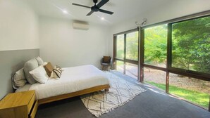 Un dormitorio con cama, ventilador de techo, ventana y vistas al exterior.